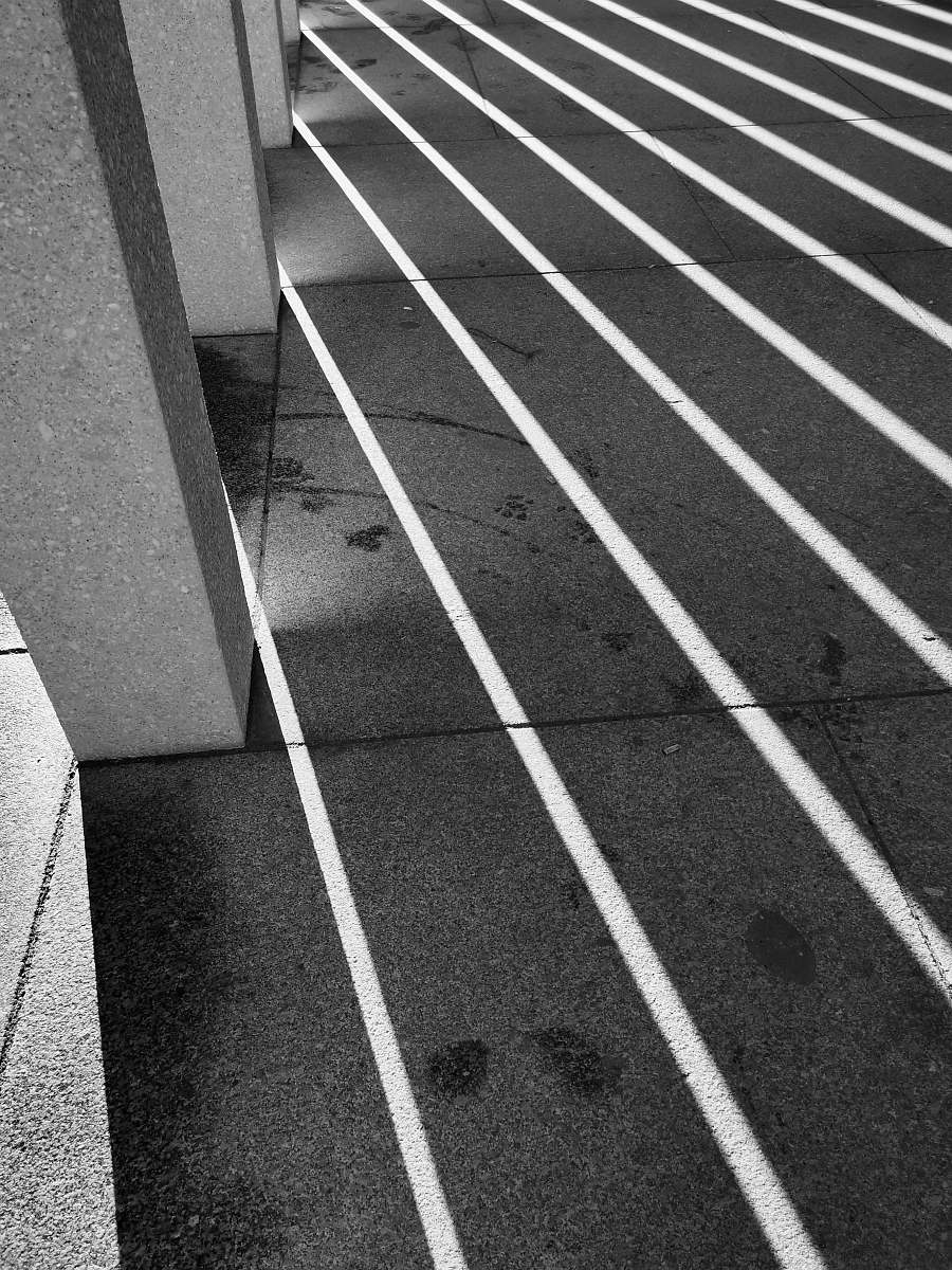running track shadows casting on paved floor black-and-white